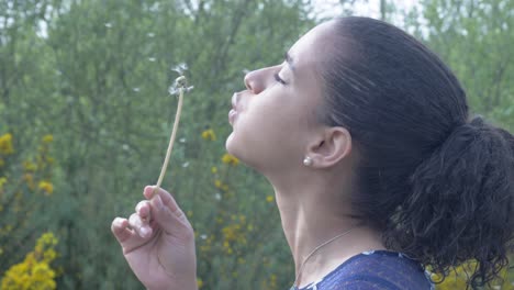 black woman blows dandelion flower