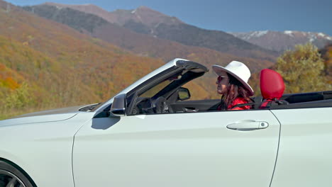 woman driving convertible through scenic autumn mountains