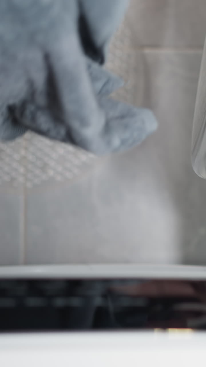 Hand in terry robe takes out clean linen from washing machine. Housewife opens washing machine after session taking out fresh towels slow motion