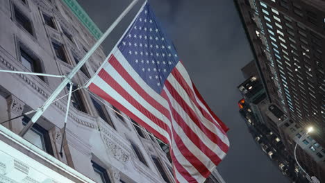 american flag flying over city buildings at night