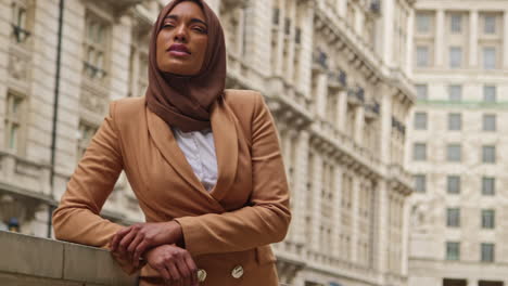 portrait of smiling muslim businesswoman wearing hijab and modern business suit standing outside city office buildings 6