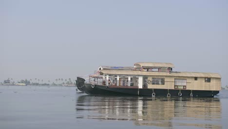 Camera-shot-gliding-slowly-over-calm-Kerala-backwaters-past-two-houseboats-in-the-afternoon-light