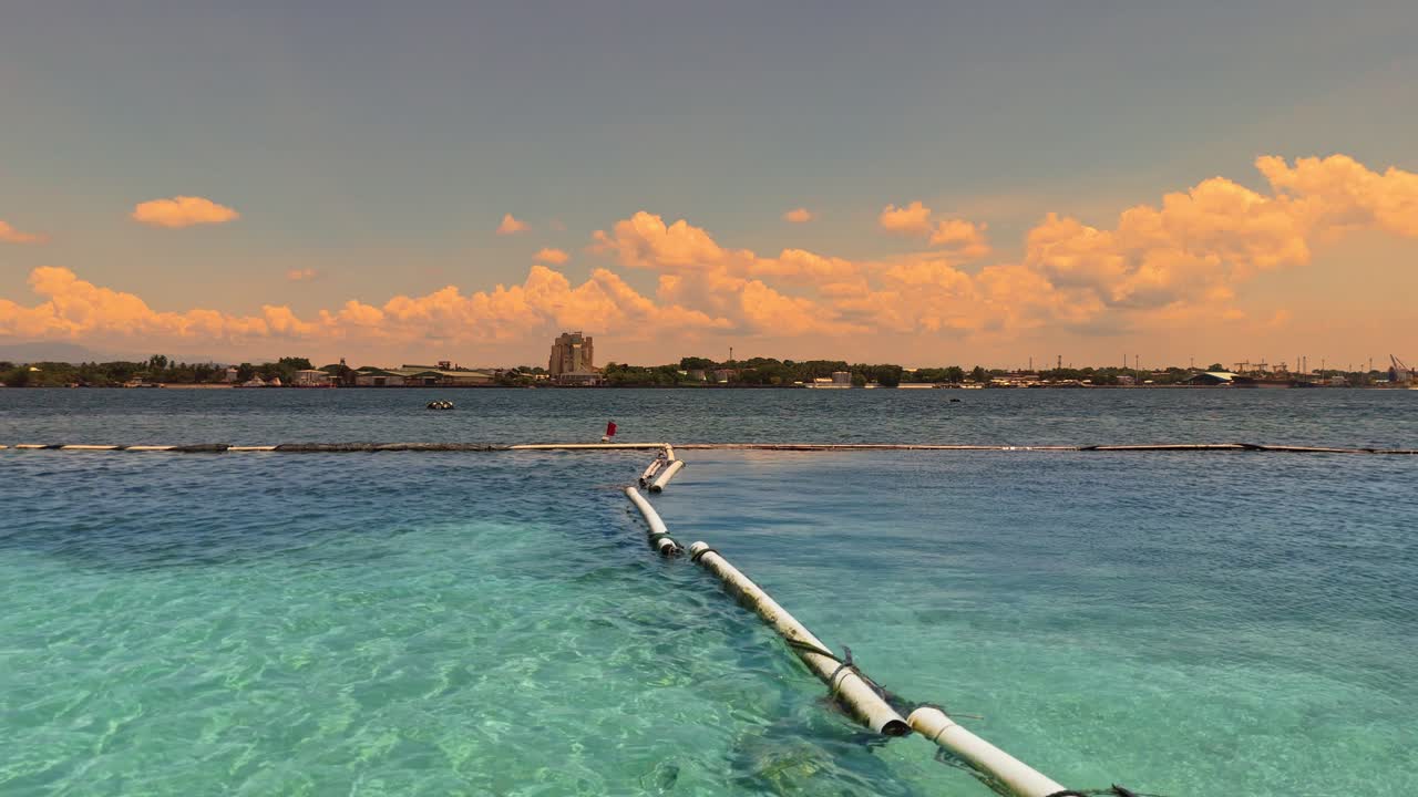 Cinematic aerial of turquoise waters and city shoreline under golden clouds in the Philippines. Ideal for travel, documentary, or environmental storytelling