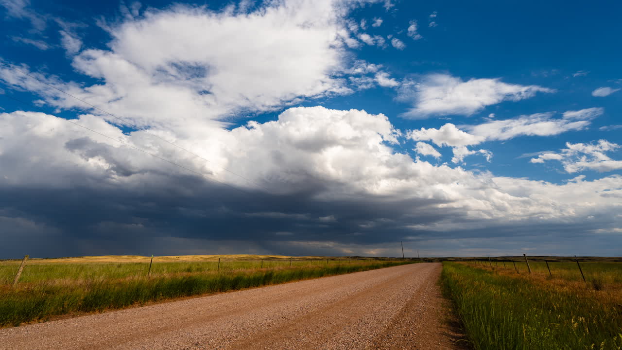 Fluffy clouds slowly moving over a quiet gravel road