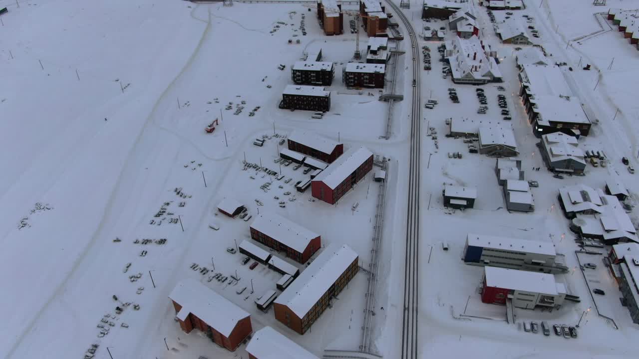 Drone view in Svalbard flying over Longyearbyen town showing houses in a snowy area with card on a road top view in Norway