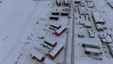 vista de avión no tripulado en svalbard volando sobre la ciudad de longyearbyen mostrando casas en un área nevada con una tarjeta en una carretera vista superior en noruega
