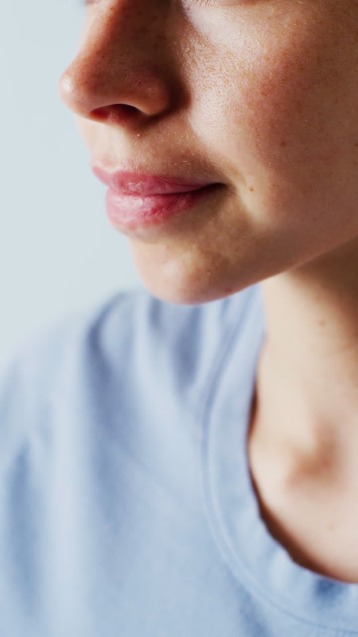 video vertical de una mujer caucásica oliendo limón sobre un fondo azul