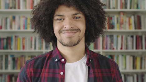 Retrato-Joven-Estudiante-Sonriente-Estantería-Biblioteca-Universidad