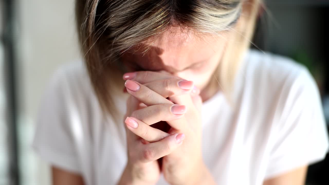 A woman with her hands clasped, appearing sad or stressed