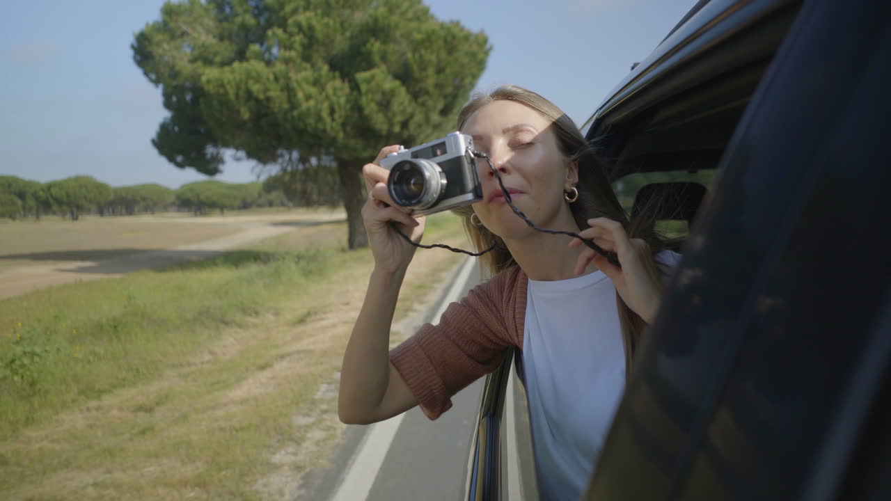 chica fotografiando con la cámara a través de la ventana abierta del coche
