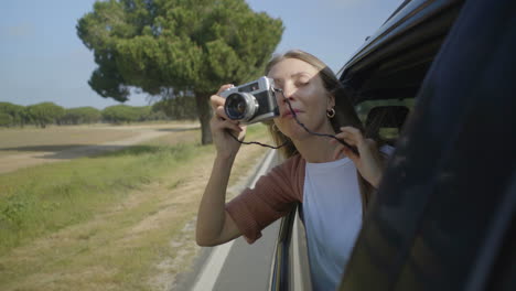 chica fotografiando con la cámara a través de la ventana abierta del coche