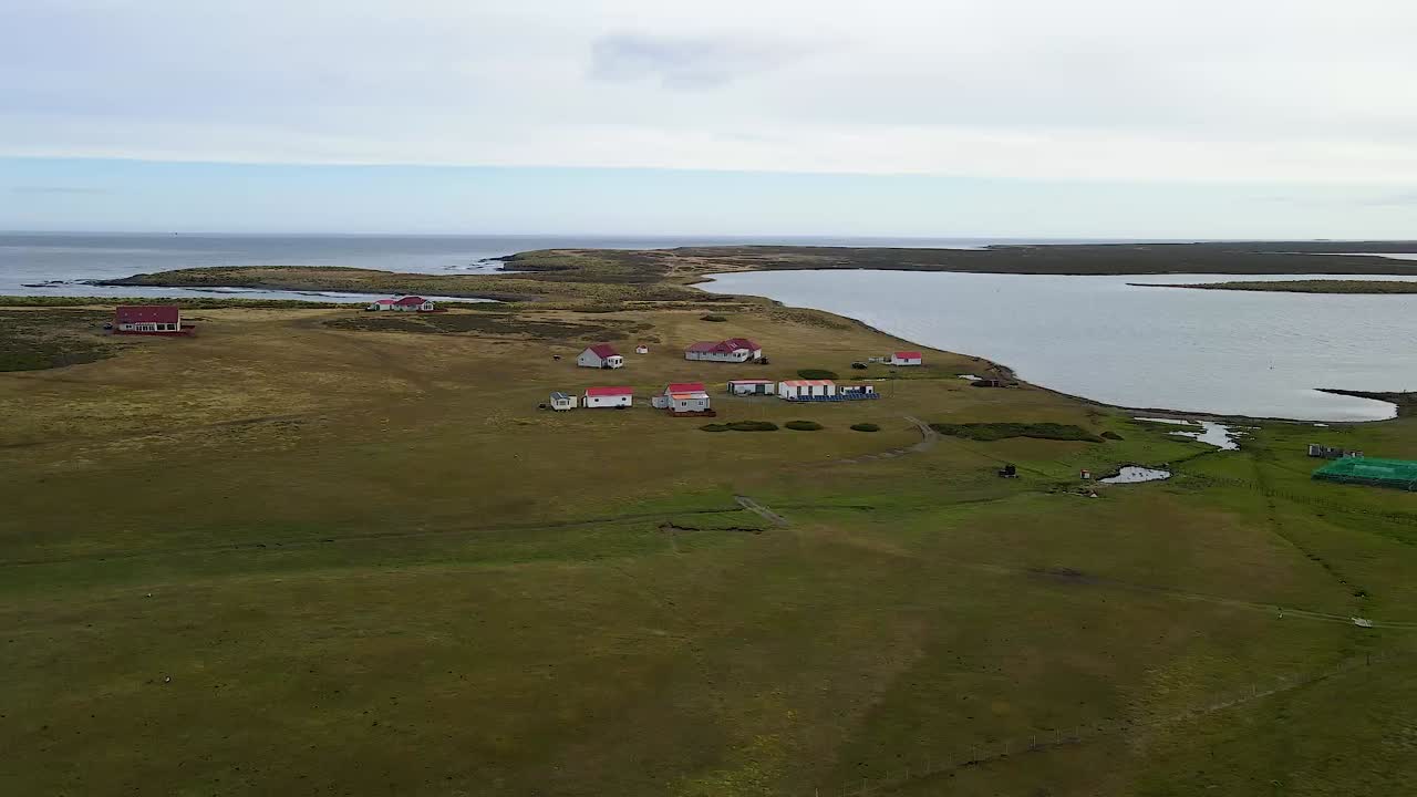 Die Kamera schwenkt über ein abgelegenes Inseldorf mit roten Dächern, das die malerische Landschaft und die ruhige Atmosphäre zur Geltung bringt.