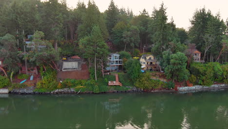 Aerial-footage-of-charming-coastal-cabins-on-Puget-Sound-at-sunrise,-bathed-in-the-soft-glow-of-early-morning-light