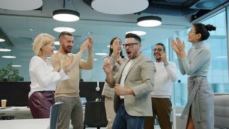 happy people employees dancing at corporate party having fun clapping hands