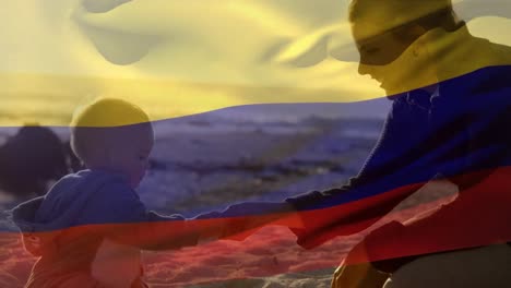 Animation-of-flag-of-colombia-over-happy-caucasian-mother-with-child-playing-at-beach