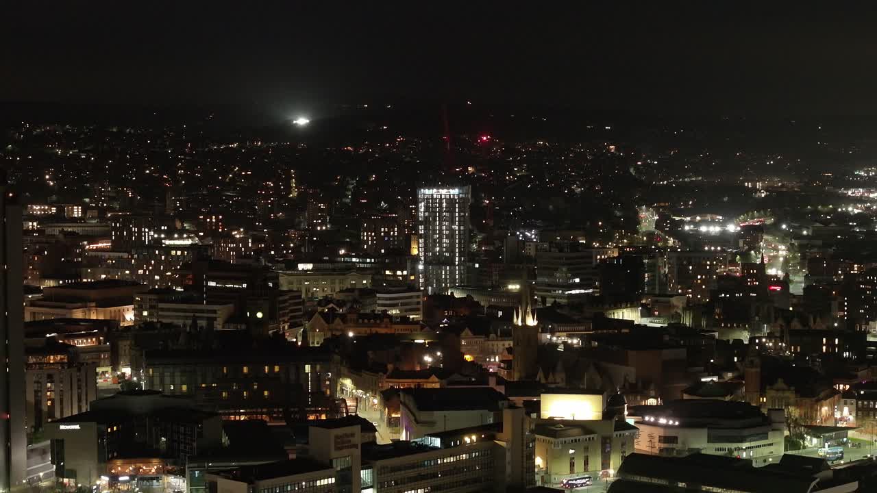 Wide rising aerial of skyline and city lights in Sheffield at night