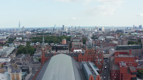 Forwards-fly-above-city.-Panoramic-view-of-urban-district.-Historic-beautiful-building-of-St-Pancras-train-station.-London,-UK