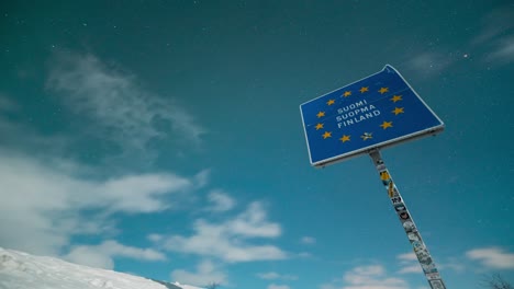 snowy border crossing sign in lapland under a starry sky, captured in timelapse