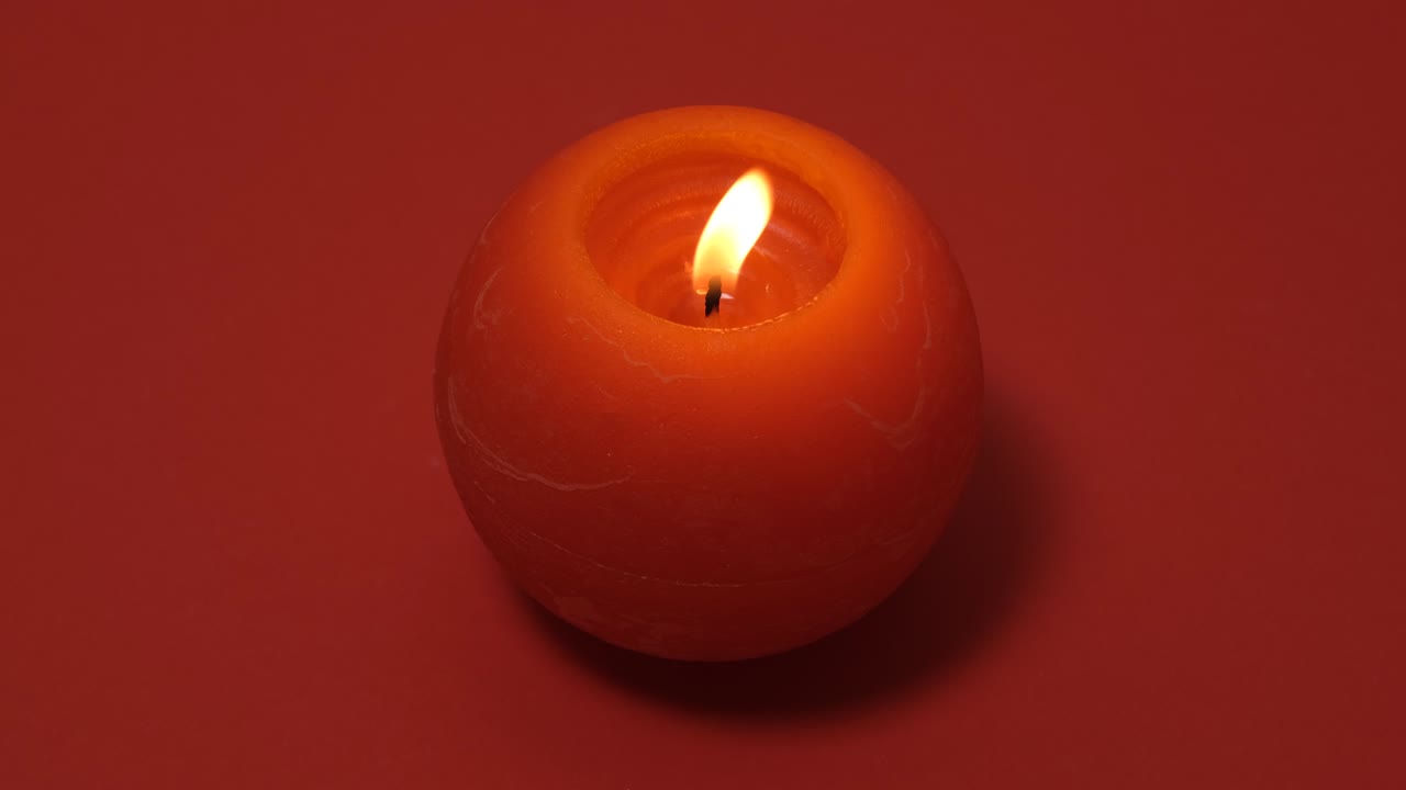 Candela rossa rotonda accesa isolata su sfondo rosso. Banner video con risoluzione 4K con candela accesa