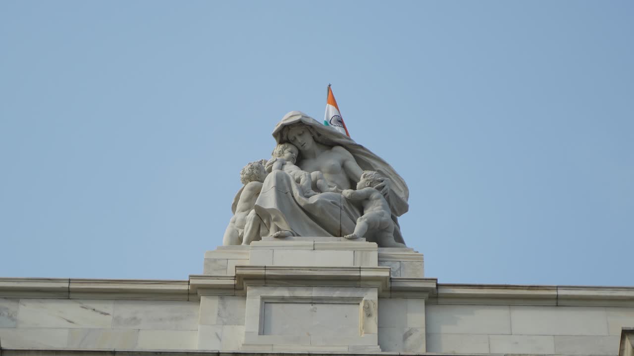 Marble statue of a woman and children on a building with an Indian flag
