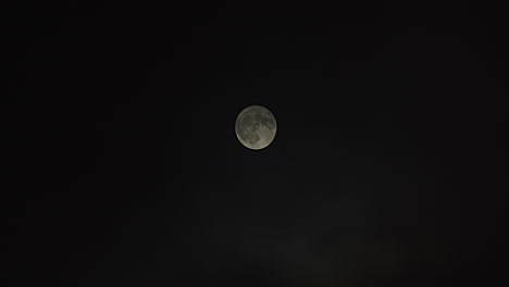 wide shot of a full moon as fog passes by revealing full moon at the end