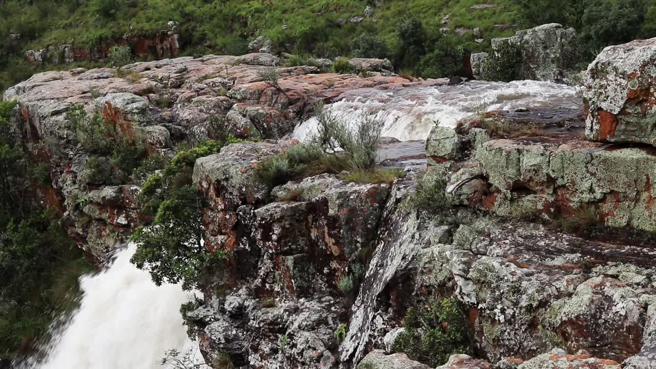 배경에 큰 물이 떨어지는 작은 물줄기가 바위 아래로 흐르는 정적 샷