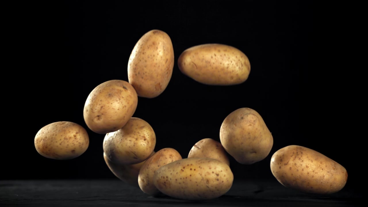 Patate fresche che cadono al rallentatore su sfondo nero