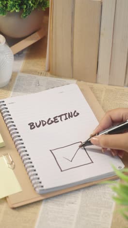 vertical video of ticking off budgeting work from checklist