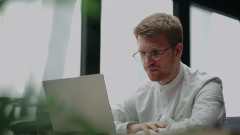 adult man is watching video on display of laptop reading news in internet portrait of person with notebook in home
