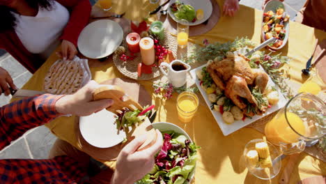 happy diverse male and female friends serving thanksgiving celebration meal in sunny garden