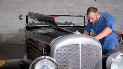 man working on a vintage car in a garage