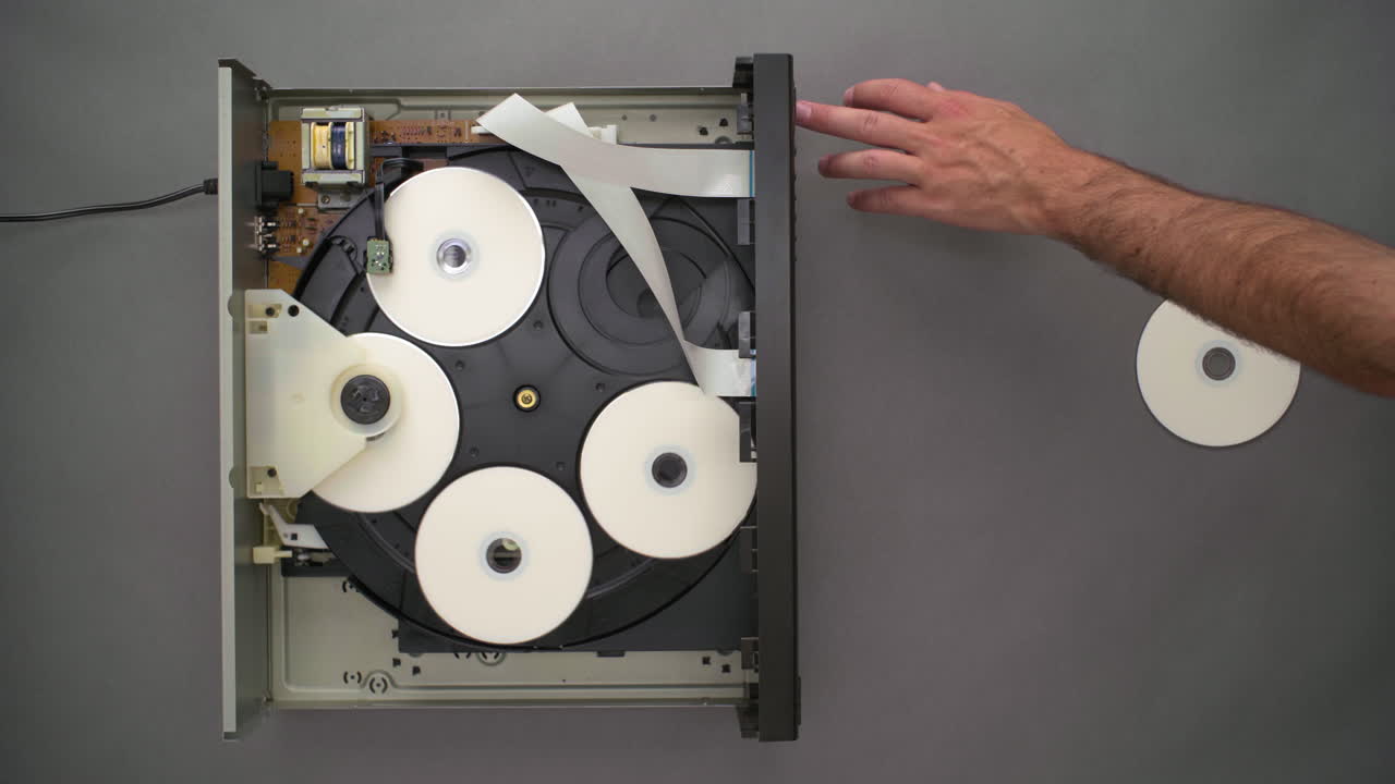 de arriba hacia abajo, la mano inserta un cd en blanco en el reproductor de cinco discos superior abierto