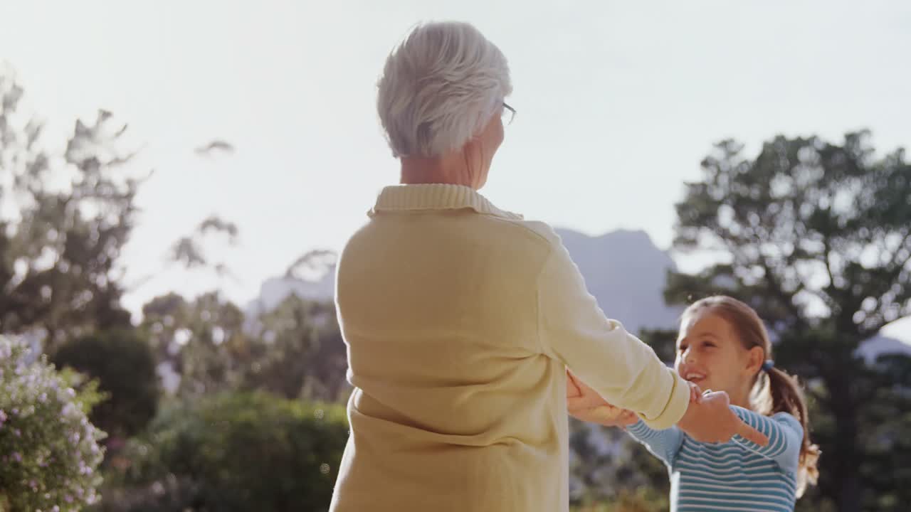 작은 소녀는 정원에서 할머니와 행복하게 춤을 추고 있습니다. 4k 4k