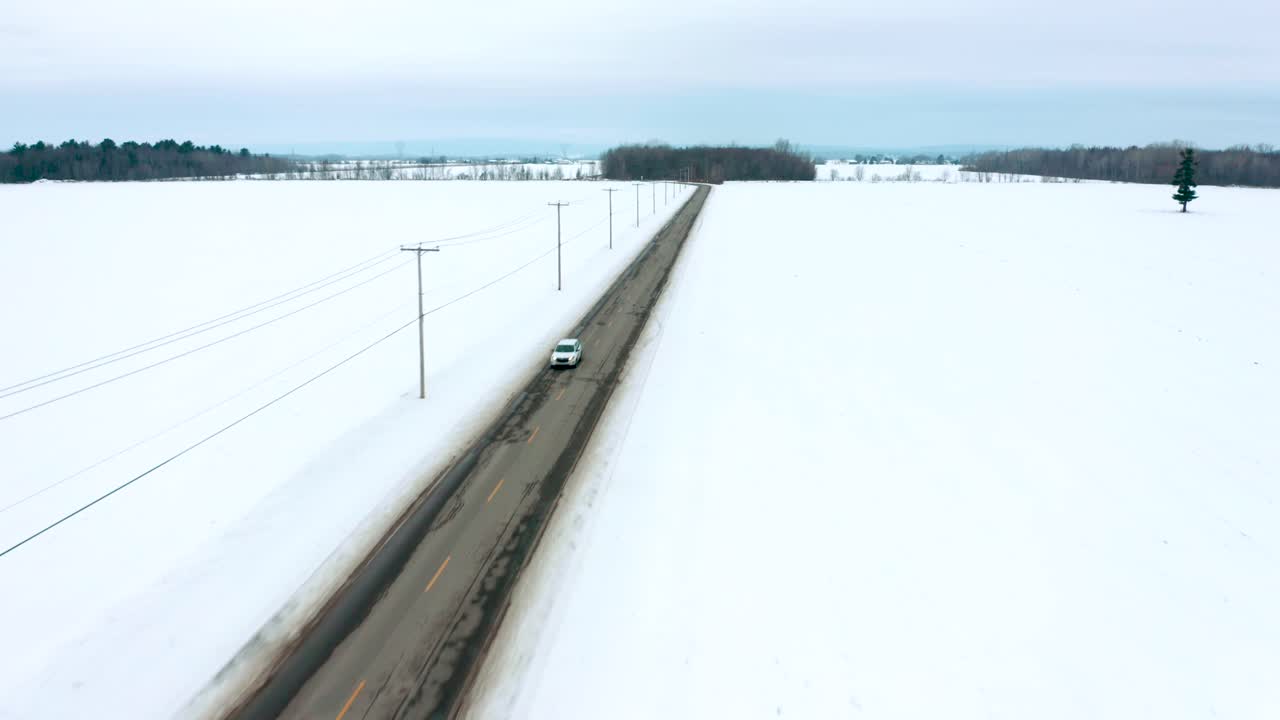 drone volando por una carretera rural cruzando un solo coche en invierno