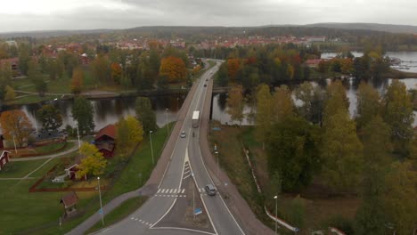 cars and trucks driving through a roundabout and over a bridge on a cloudy autumn day