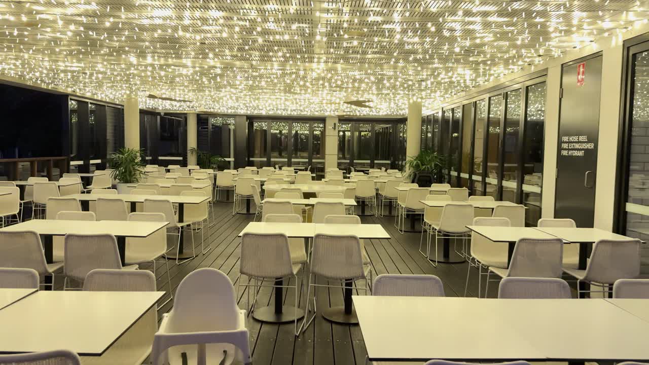 An empty restaurant in Gold Coast, Australia, with twinkling ceiling lights and modern decor, captured in a serene nighttime setting