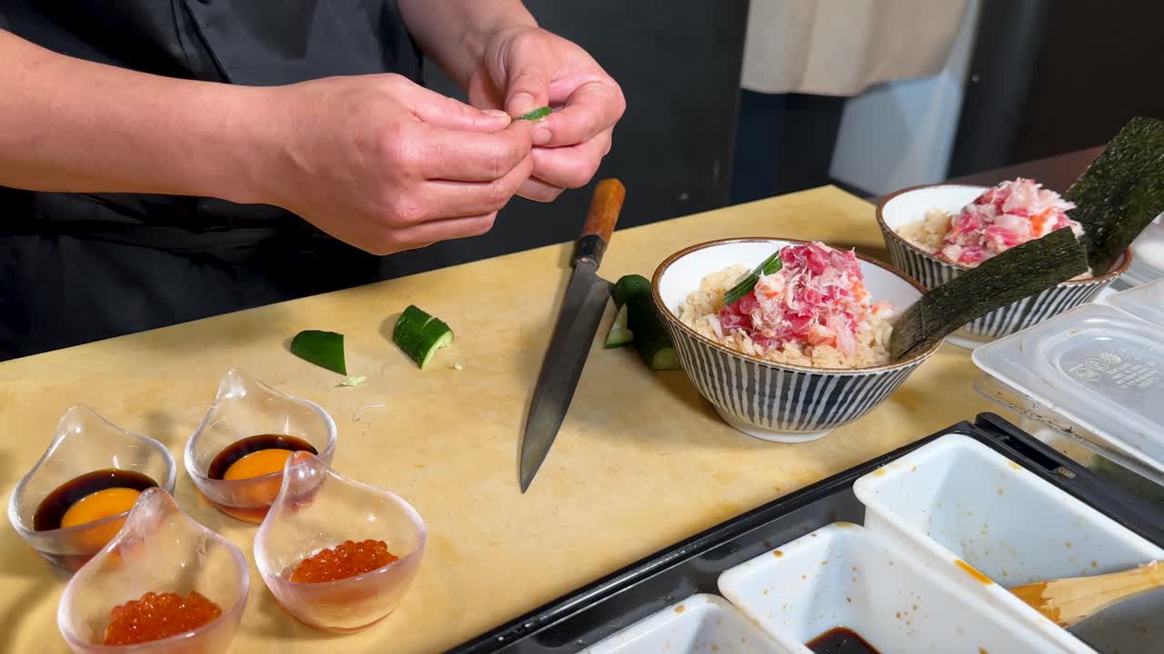 Close-up shot of a chef's hands meticulously placing garnishes on a fresh sashimi bowl