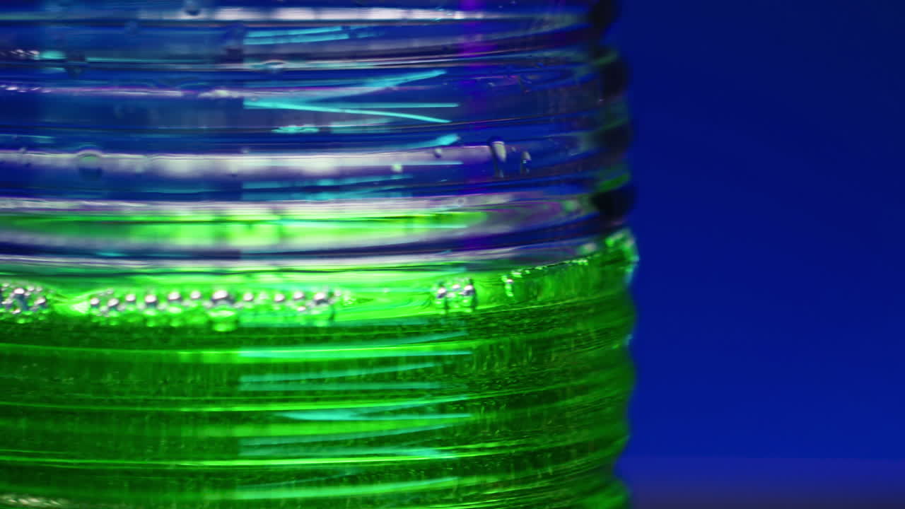 primer plano de una botella de plástico colorida con líquido verde y burbujas