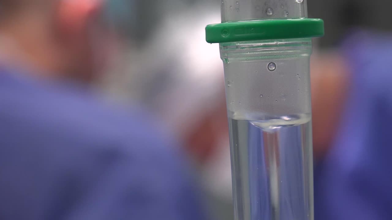 Conta-gotas médico cirúrgico em fundo desfocado de médicos na sala de cirurgia.