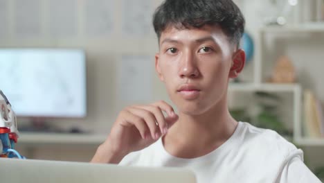 アジアの男の子が自宅のラップトップでサイボルグの手について考えて指を上げている