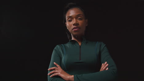 retrato de una atleta femenina decidida que lleva un traje de entrenamiento y se prepara psicológicamente para un evento deportivo contra un fondo de estudio negro 3