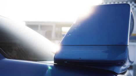 Alerón-Trasero-De-Coche-Azul-De-Rally-Deportivo-Con-Brillo-Solar-En-El-Fondo-Durante-El-Soleado-Día-De-Invierno