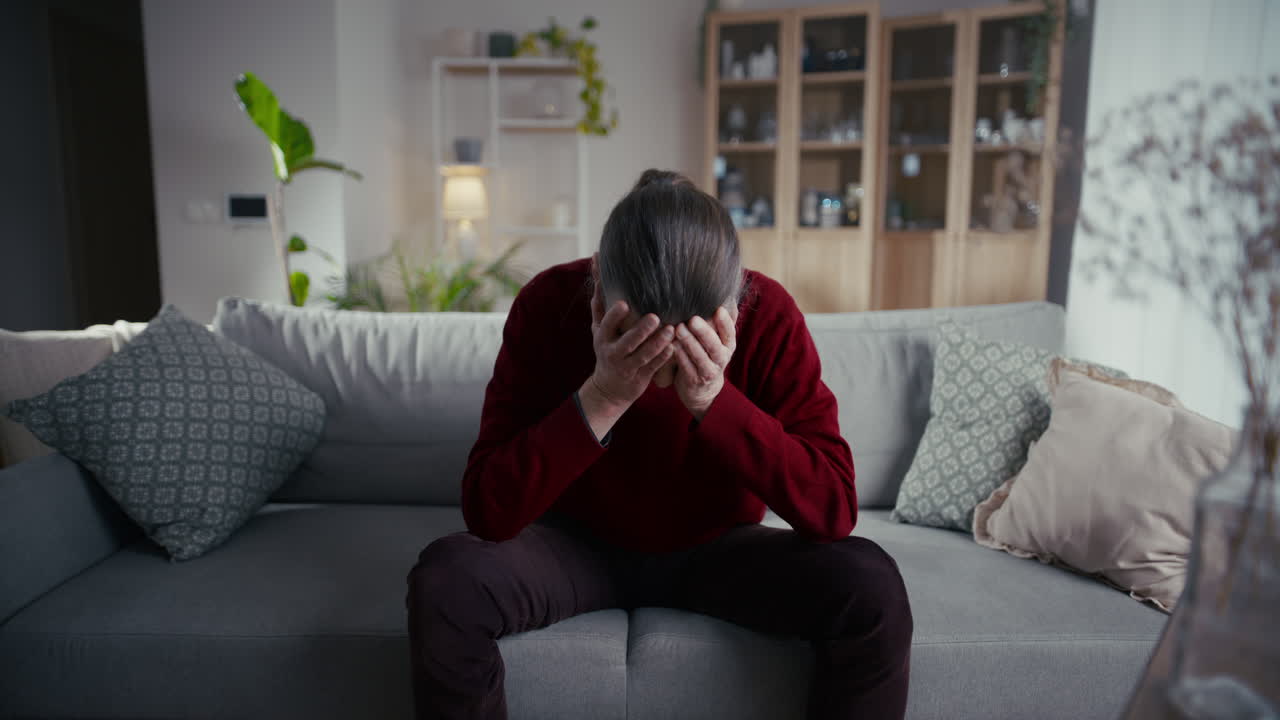 Depressed Senior Man Covering Face with Hands on Sofa