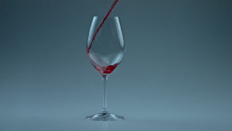 closeup spirituous liquid splashing inside wineglass. wine pouring clean goblet