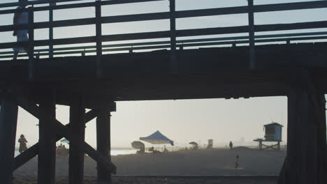 a small child runs under a silhouetted pier