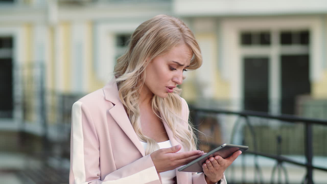 Primo piano di donna che lavora sul tablet per strada. Donna che usa un tablet in tailleur rosa.