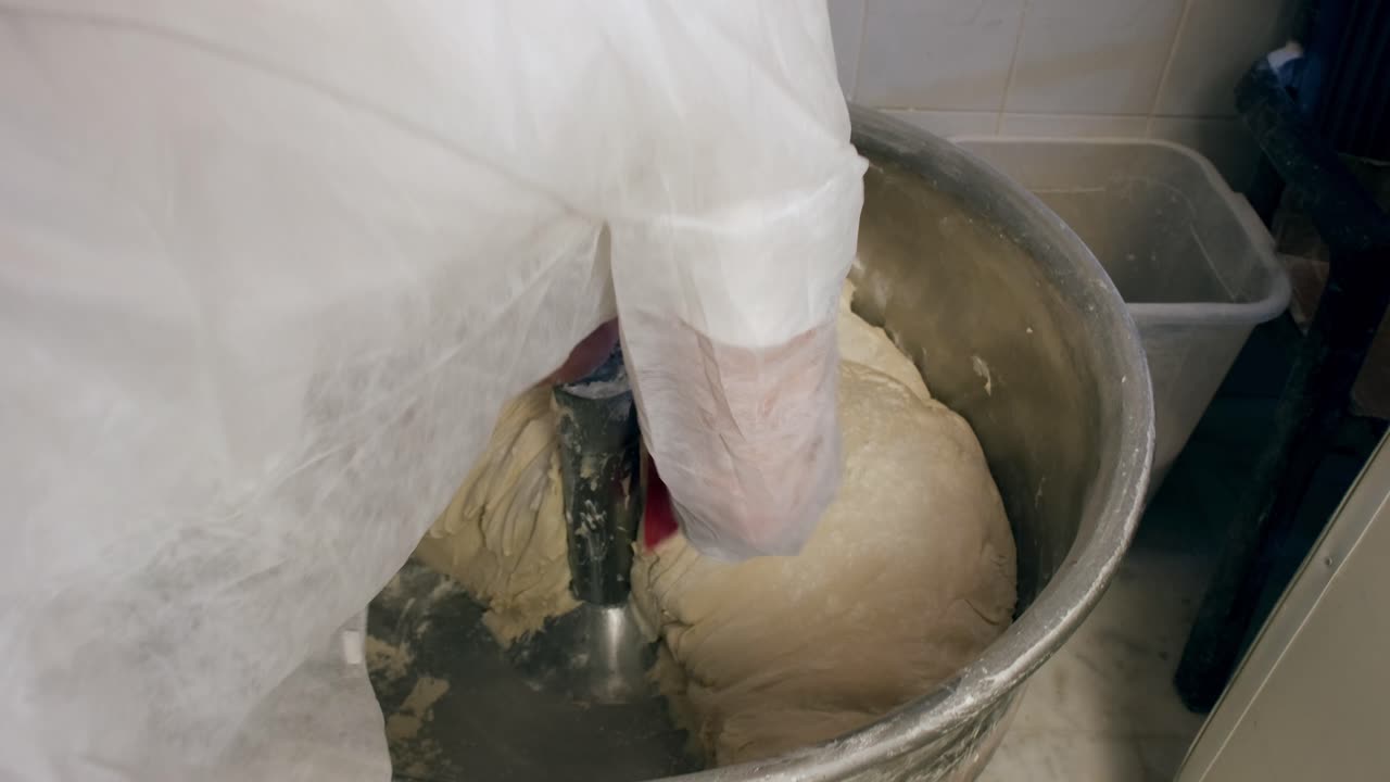 il panettiere aggiunge farina all'impasto impastato