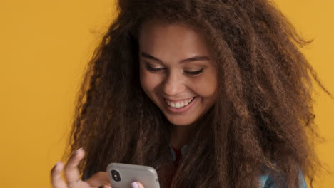 mujer caucásica de pelo rizado desplazándose en el teléfono inteligente.