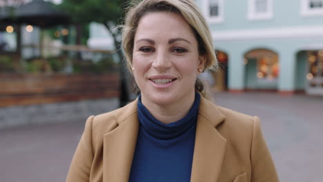 slow motion portrait of stylish blonde business woman in suit smiling cheerful at camera urban background