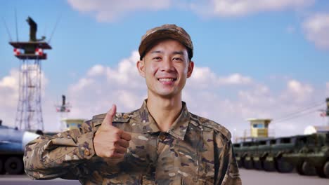 close up of asian man soldier smiling and showing thumbs up gesture while standing at military camp